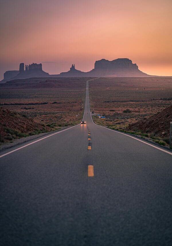 Vertical image of an empty two lane highway with mountains in the background