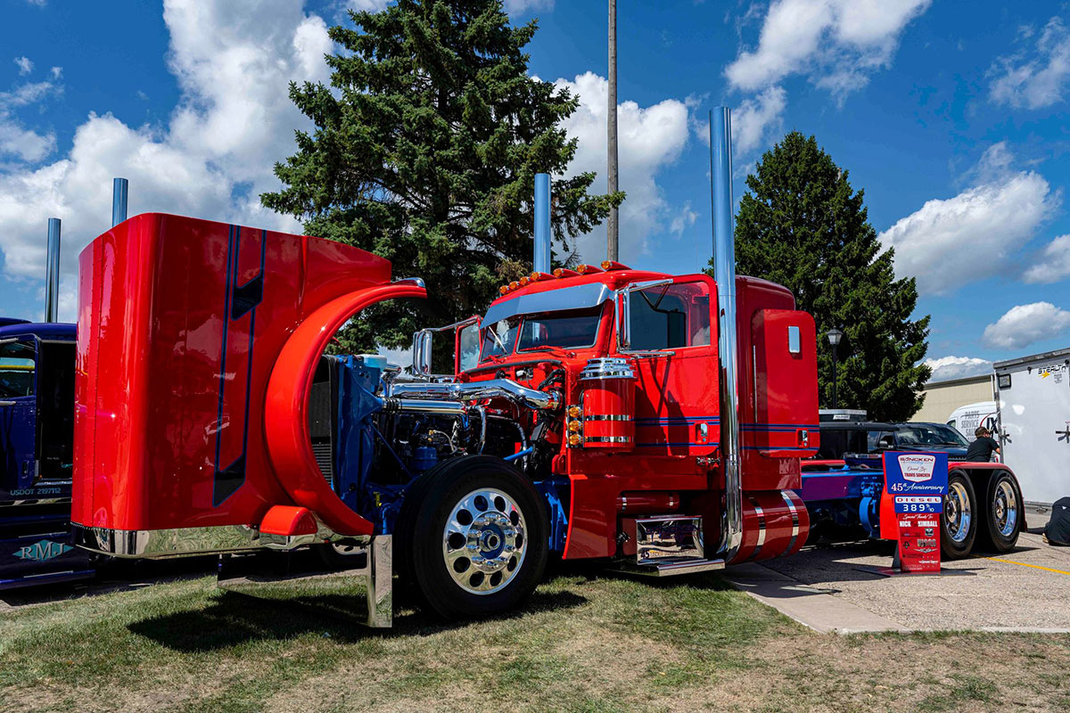 Red Peterbilt with blue graphics, hood open to see engine